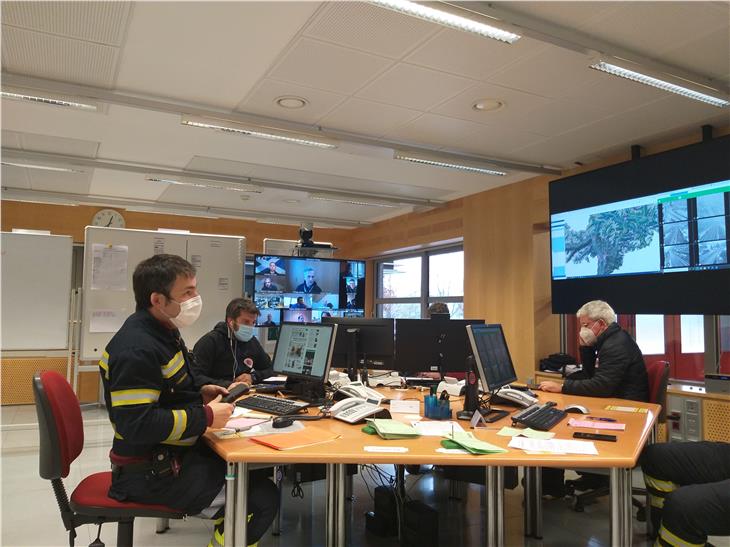 Bewertungskonferenz  Landeswarnzentrum: Vorsitzender Gallmetzer (Videobildschirm Bildmitte), Direktor der Agentur für Bevölkerungsschutz Pollinger (re.), Leiter Stab im Lagezentrum der Berufsfeuerwehr Lazzarotto (li.). (Foto: LPA/Maja Clara)